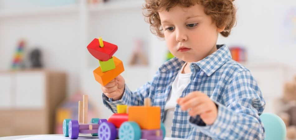 Cute,little,boy,playing,with,wooden,toys,at,white,table