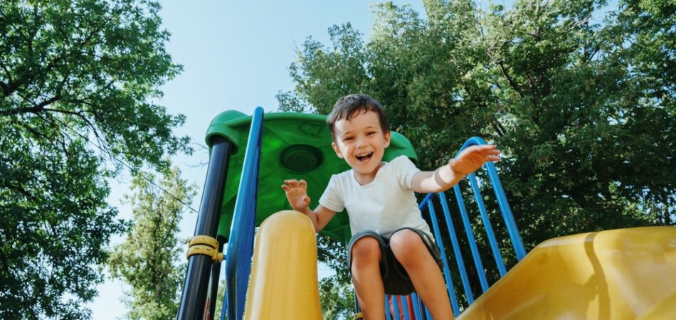 Happy,preschooler,boy,playing,on,a,slide,on,the,playground