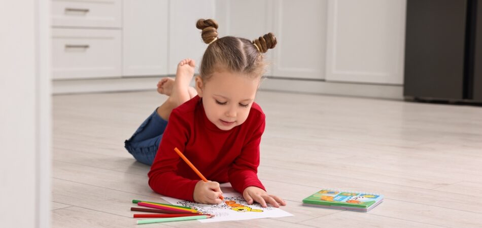 Cute,little,girl,coloring,drawing,on,warm,floor,in,kitchen.